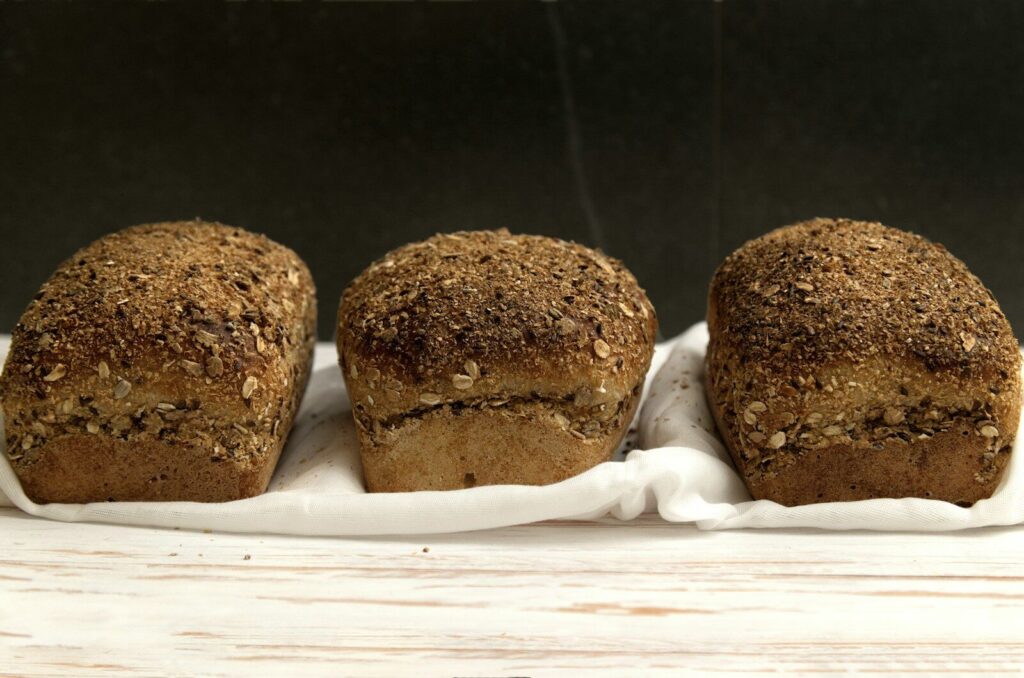Three loaves of whole grain bread on a white cloth